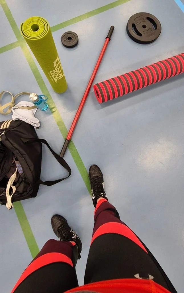 Kuvassa treenivälineitä lattialla ja kuvassa näkyy kuvaajan jalat